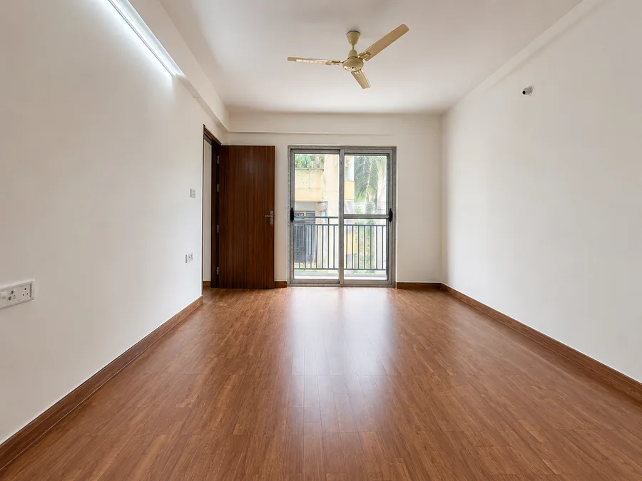 Master bedroom of the model flat with laminate wood flooring and a glazed door opening to the balcony